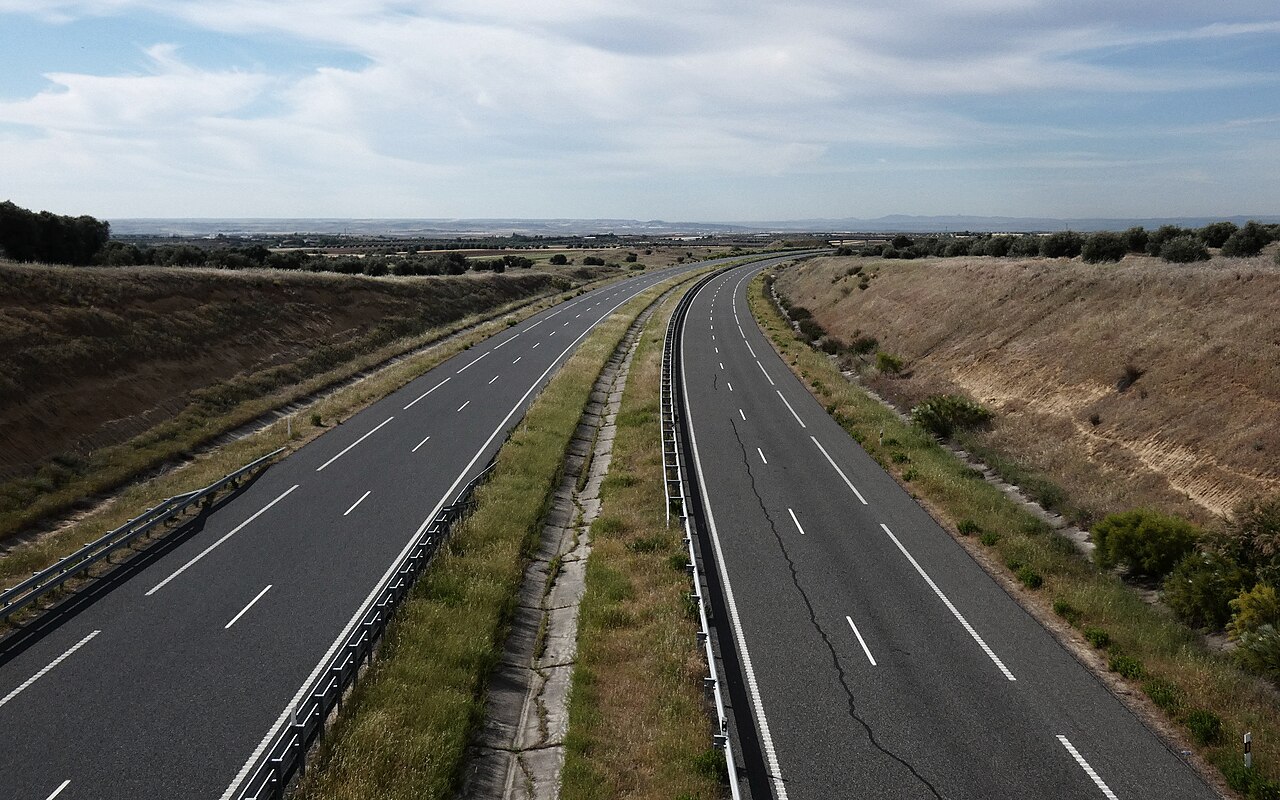 Autopista de dos calzadas en un paisaje seco, vista desde un puente.