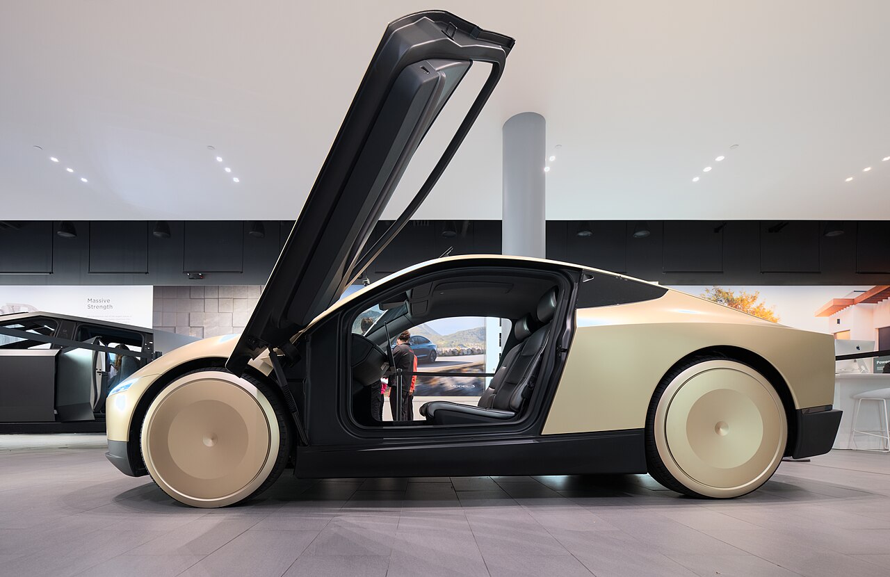 Tesla Cybercab de color arena, con la puerta de ala abierta, en un interior.