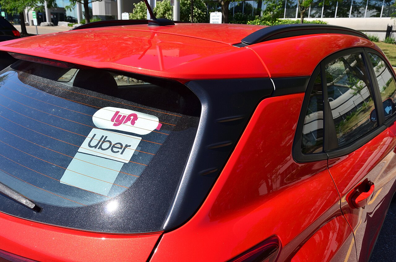 Luneta de un coche rojo con los distintivos de Lyft y Uber.